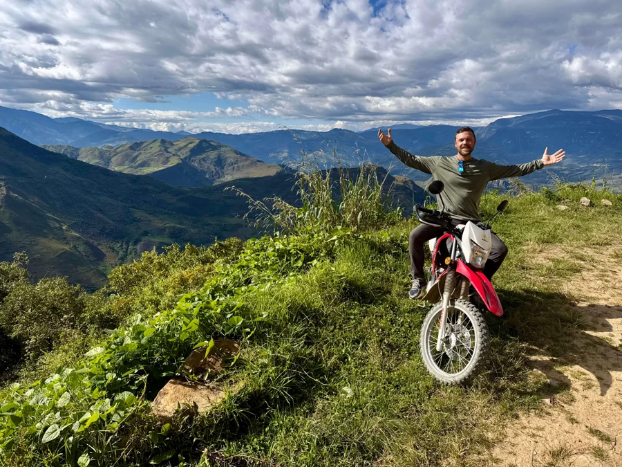 Joseph with his motorcycle overlooking a mountain valley in Peru